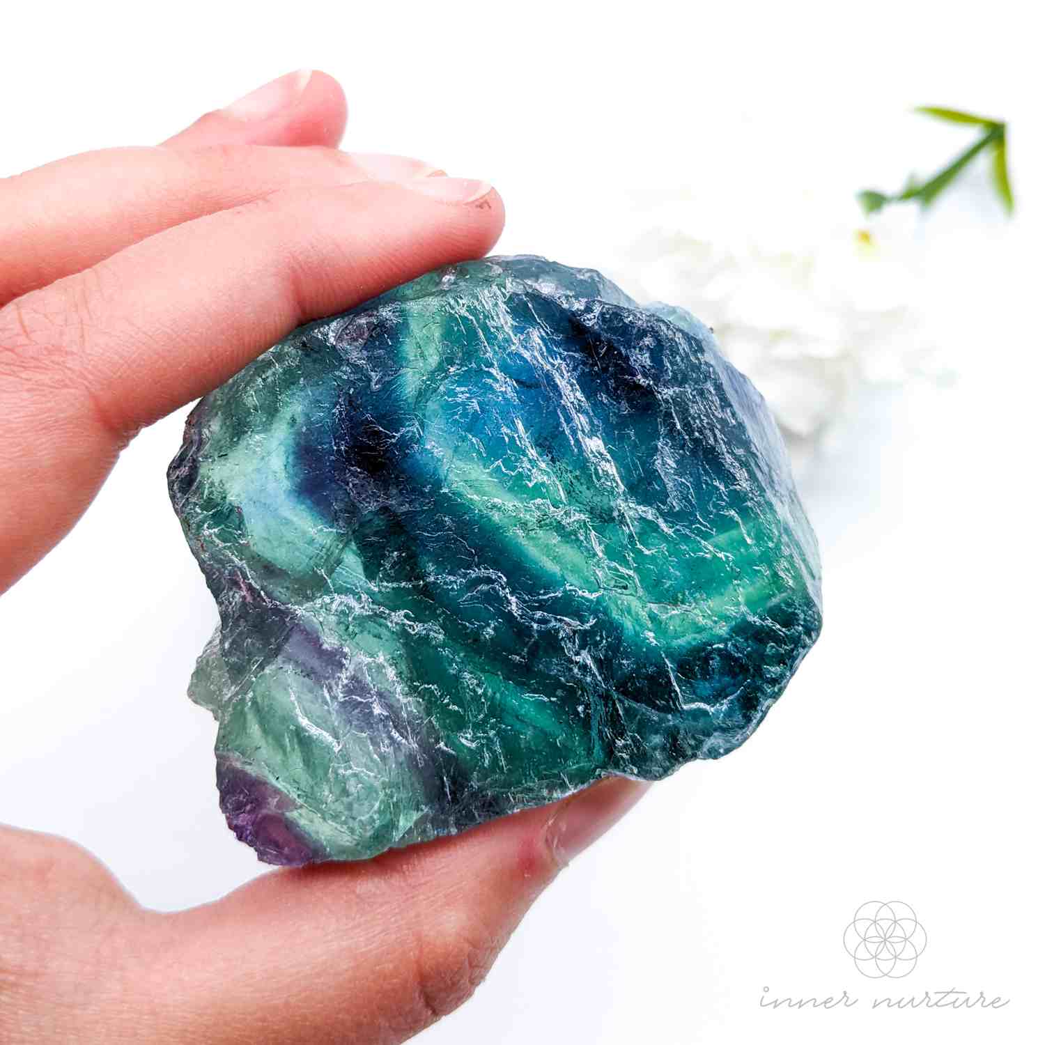 rainbow fluorite blue green and purple raw specimen, held in a hand. sold at inner nurture, an online crystal shop in australia
