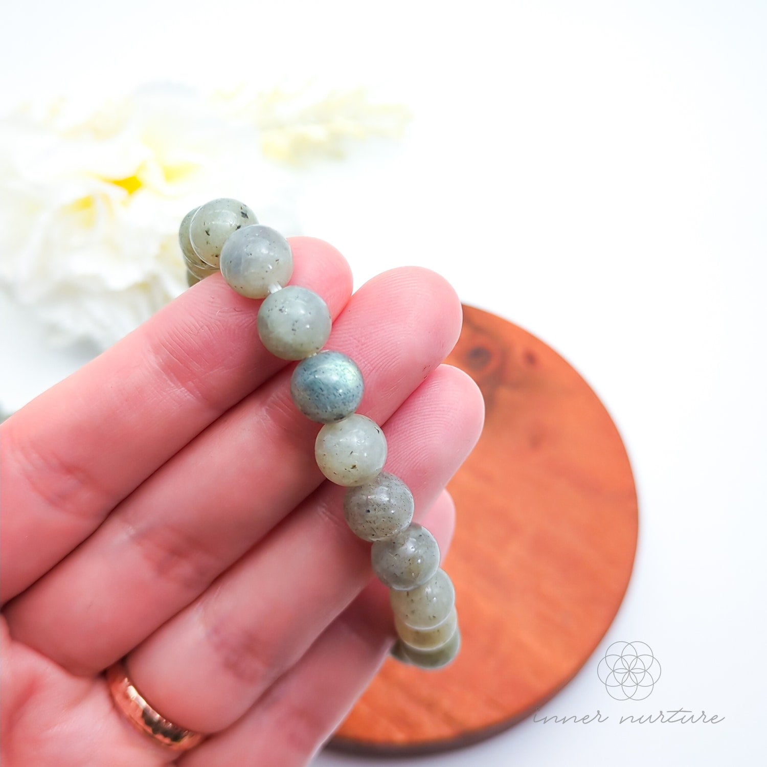 Beaded bracelet on a wooden coaster. Labradorite bead bracelet sold by Inner Nurture, an online australian crystal shop.