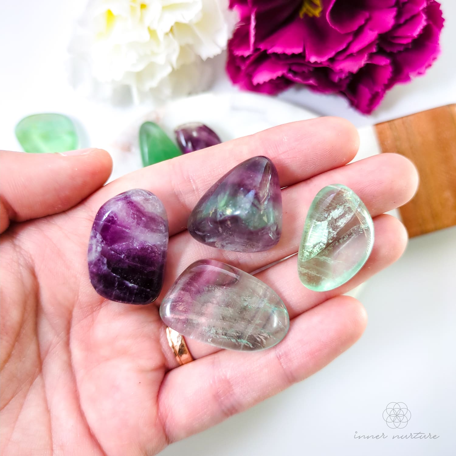 hand holding rainbow fluorite tumbles. available online at inner nurture, an online crystal shop in australia