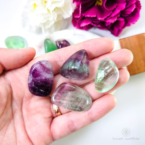 hand holding rainbow fluorite tumbles. available online at inner nurture, an online crystal shop in australia