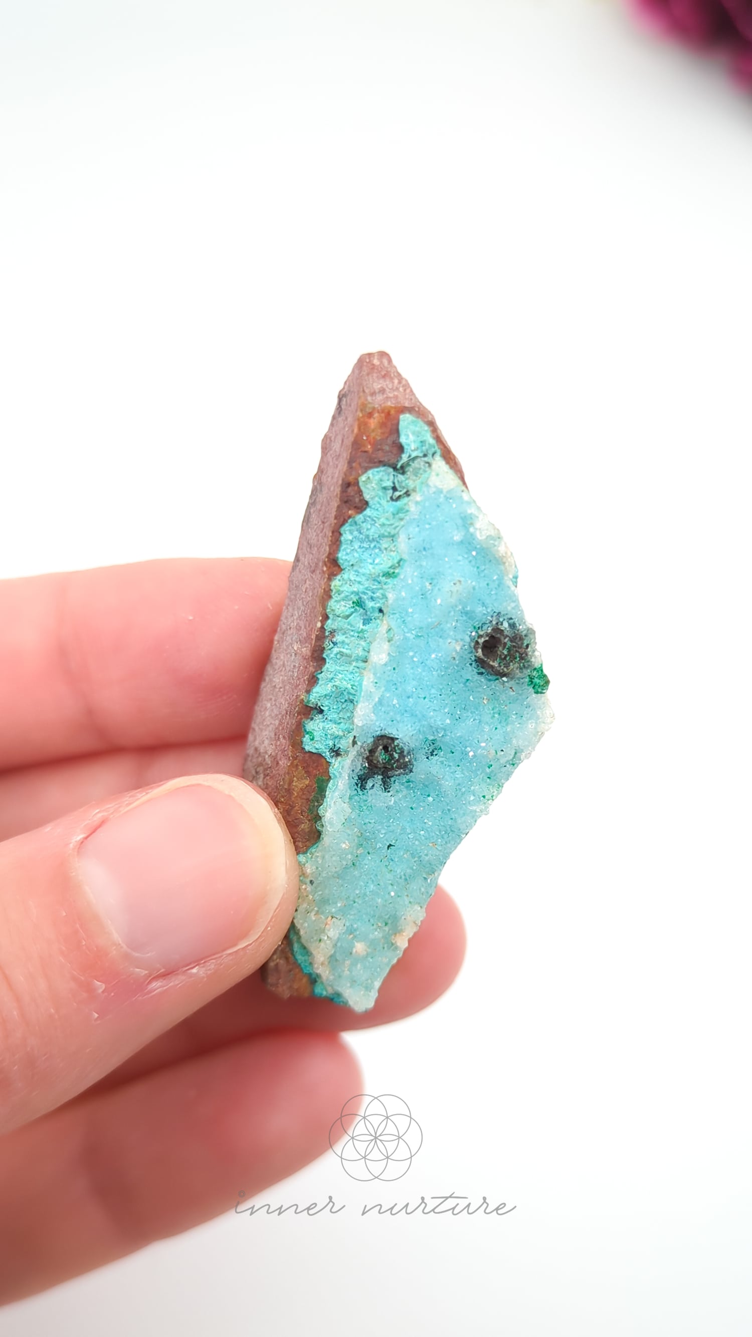 Hand holding a geode crystal with blue interior and brown exterior against a white background. Malacolla Specimen, Drusy Coated On Dolomite - #13 at Crystal Shop Online Australia called Inner Nurture