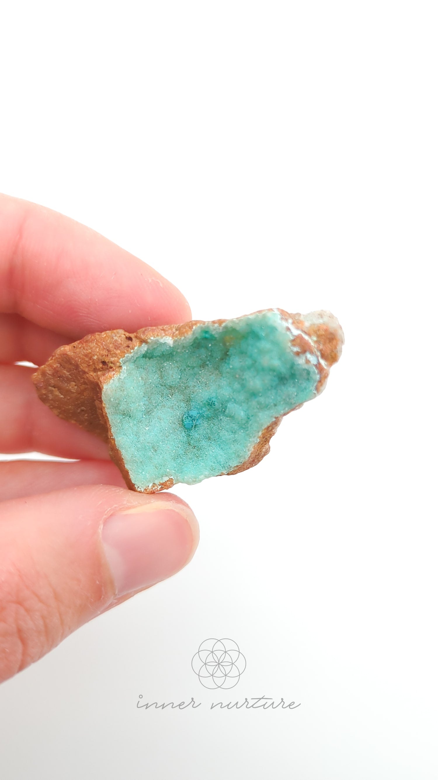 Hand holding a turquoise crystal against a white background. Malacolla Specimen, Drusy Coated On Dolomite - #16 at Crystal Shop Online Australia called Inner Nurture