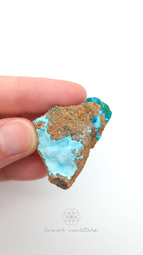 Turquoise stone held between fingers against a white background. Malacolla Specimen, Drusy Coated On Dolomite - #24 at Crystal Shop Online Australia called Inner Nurture