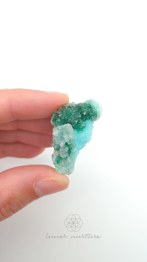 Hand holding a green and white crystal against a white background. Malacolla Specimen, Drusy Coated On Dolomite - #25 at Crystal Shop Online Australia called Inner Nurture