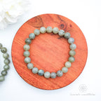 Beaded bracelet on a wooden coaster. Labradorite bead bracelet sold by Inner Nurture, an online australian crystal shop. 