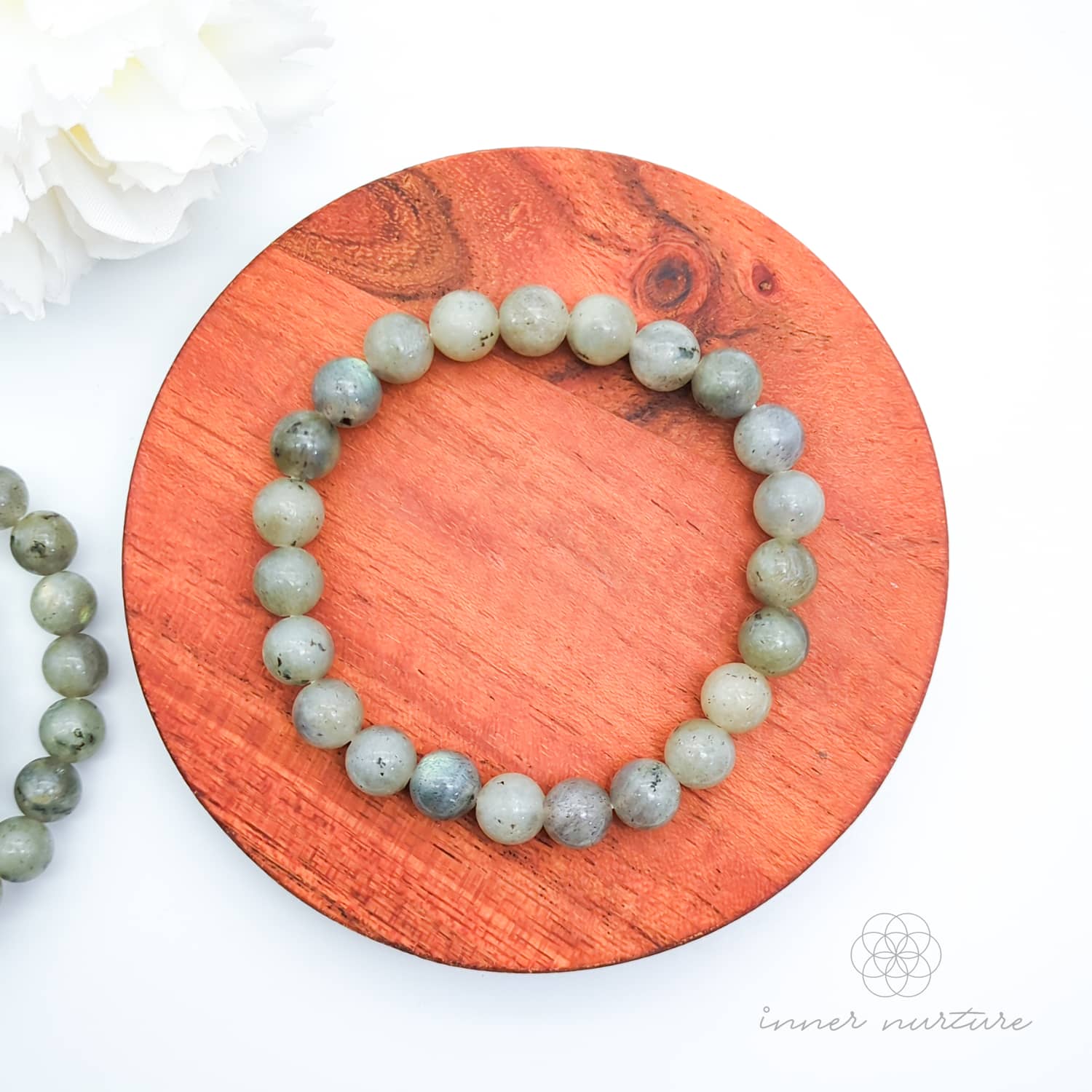 Beaded bracelet on a wooden coaster. Labradorite bead bracelet sold by Inner Nurture, an online australian crystal shop. 