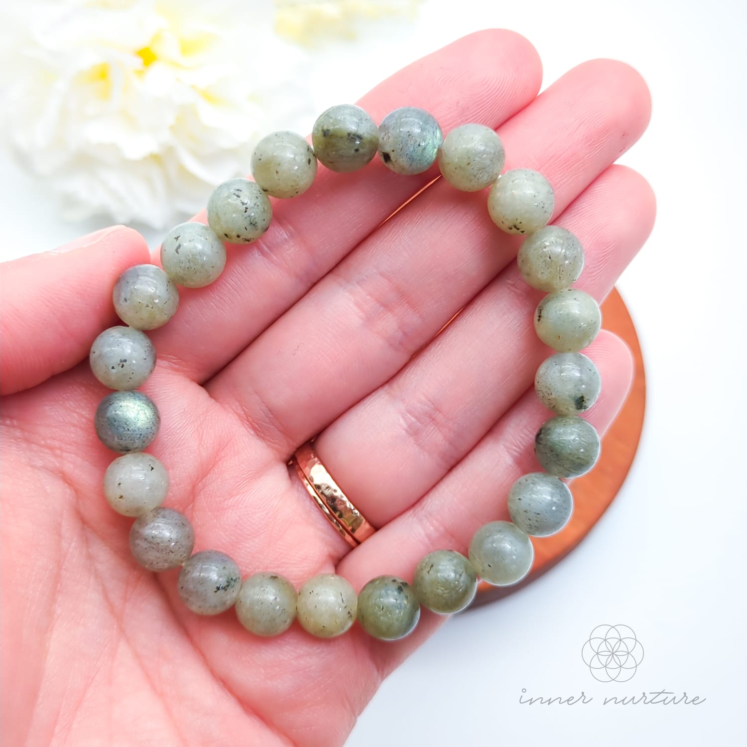 Beaded bracelet on a wooden coaster. Labradorite bead bracelet sold by Inner Nurture, an online australian crystal shop. 