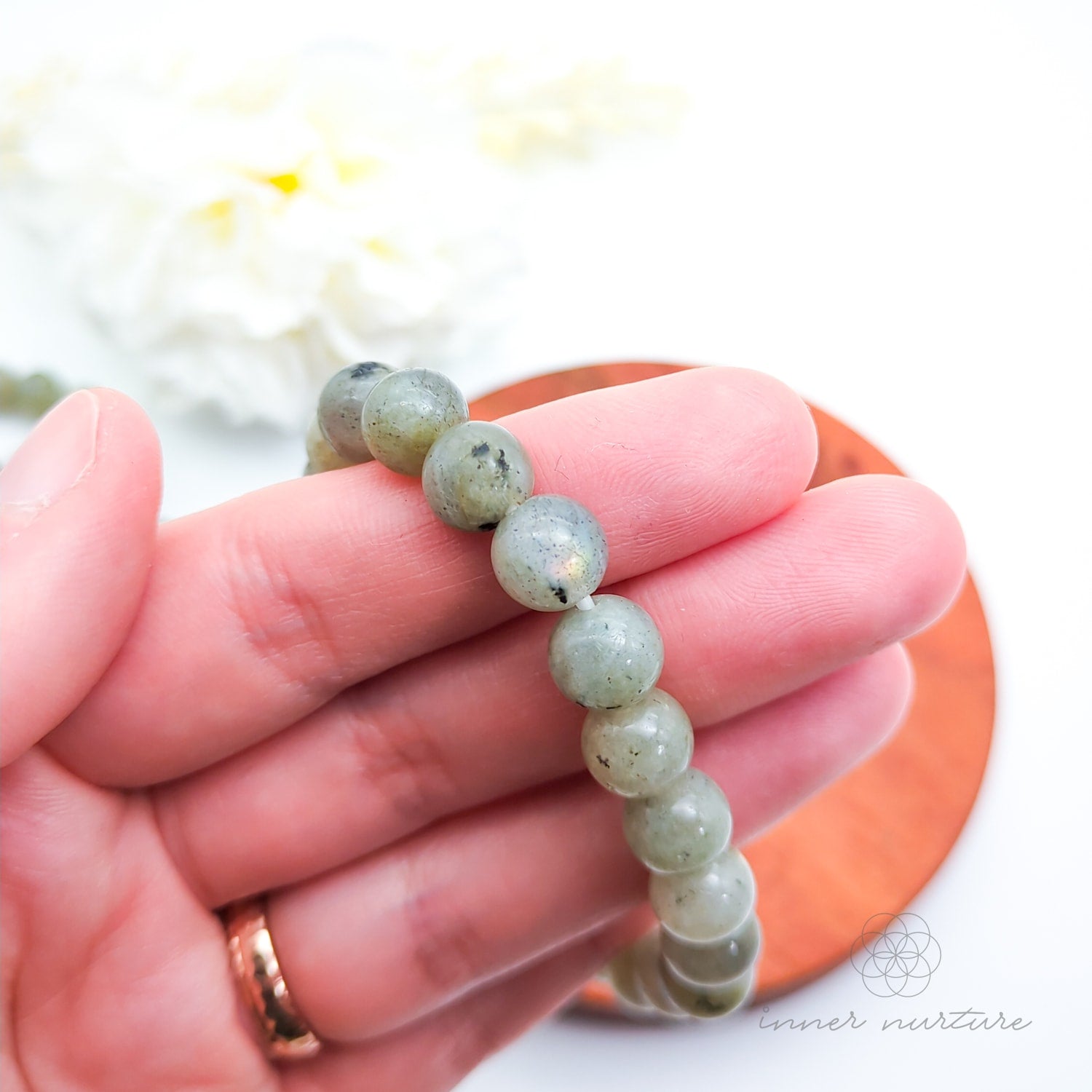 Beaded bracelet on a wooden coaster. Labradorite bead bracelet sold by Inner Nurture, an online australian crystal shop. 