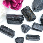Black crystals on a white surface with a pink flower in the background. Available online at Inner Nurture, an Australian crystal store. 