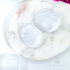 Two crystal stones on a marble surface with 'inner nurture' branding. Selenite palm stone available at Inner Nurture, an online crystal shop in Australia.