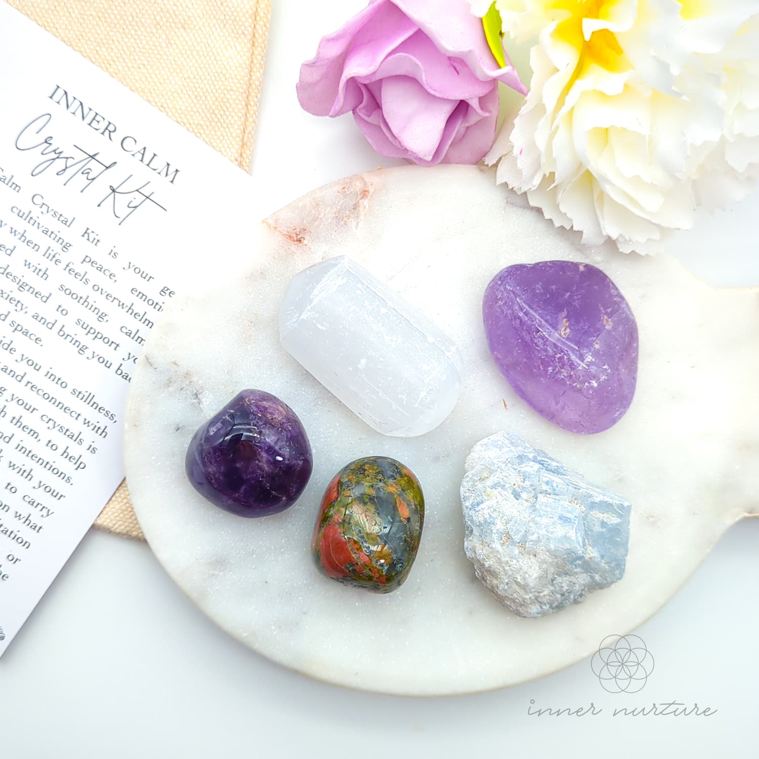 Set of crystals on a marble surface with flowers and a card. Inner Calm Crystal Kit, available on line in Australia at Inner Nurture