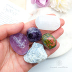 Hand holding four colorful crystals with a blurred background.  Inner Calm Crystal Kit, available on line in Australia at Inner Nurture