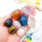 Hand holding a collection of colorful crystals with a blurred background. Chakra Balancing Crystal Kit, available on line in Australia at Inner Nurture