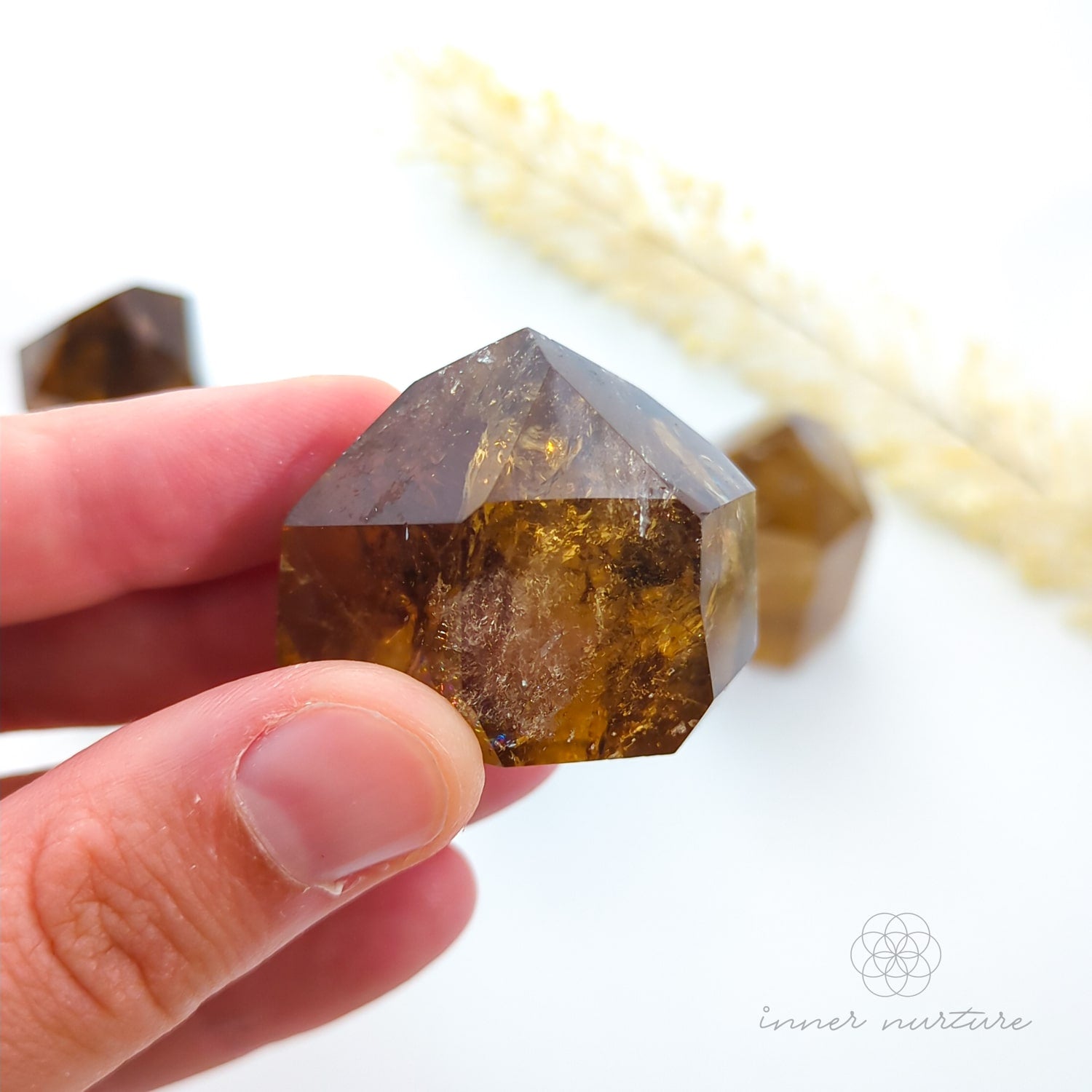 Hand holding a brown crystal with a blurred background. Set of crystal points on a white background with 'inner nurture' branding. Citrine (Natural) Tower for Abundance & Manifestation | Crystals Australia Inner Nurture