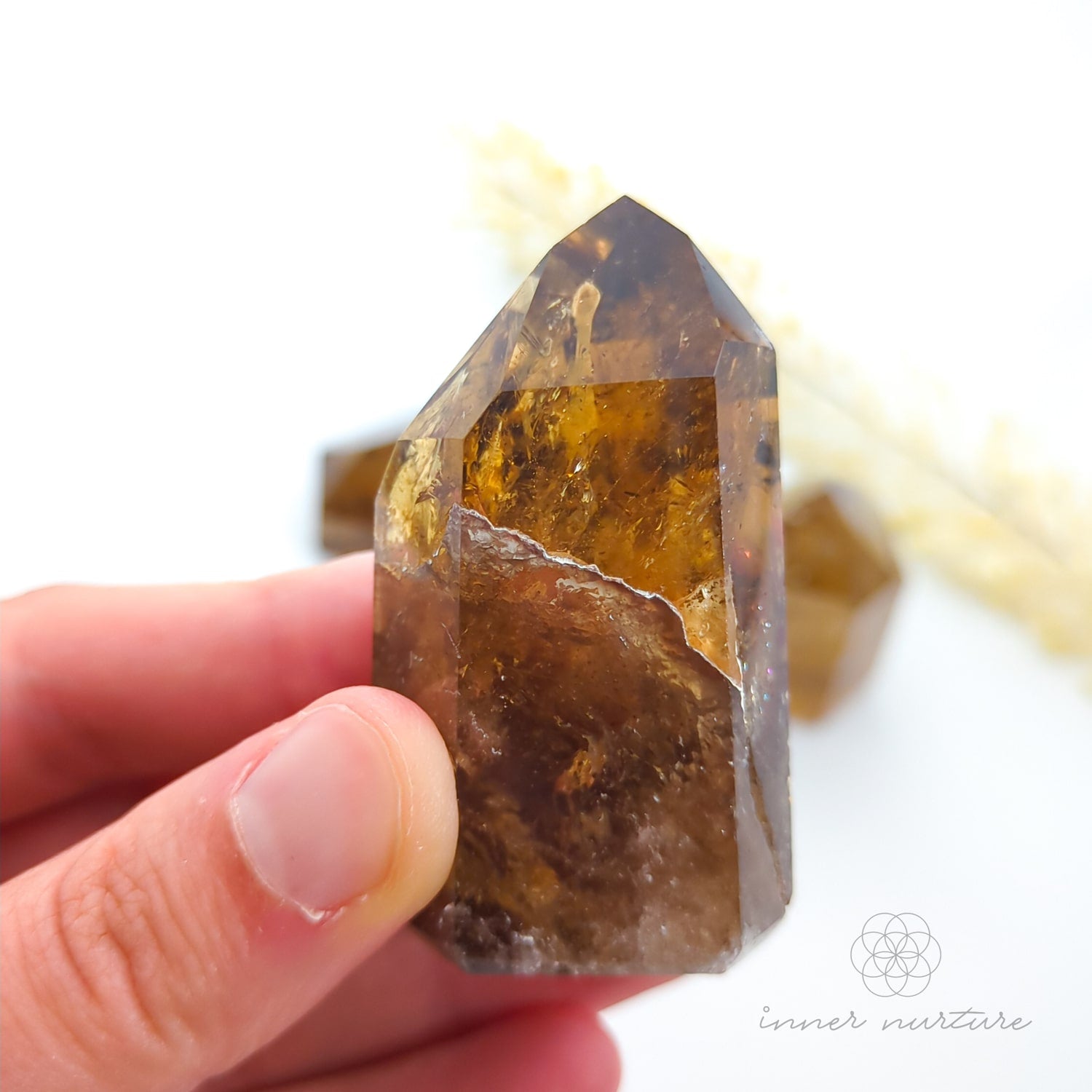 Hand holding a brown crystal with a blurred background. Set of crystal points on a white background with 'inner nurture' branding. Citrine (Natural) Tower for Abundance & Manifestation | Crystals Australia Inner Nurture
