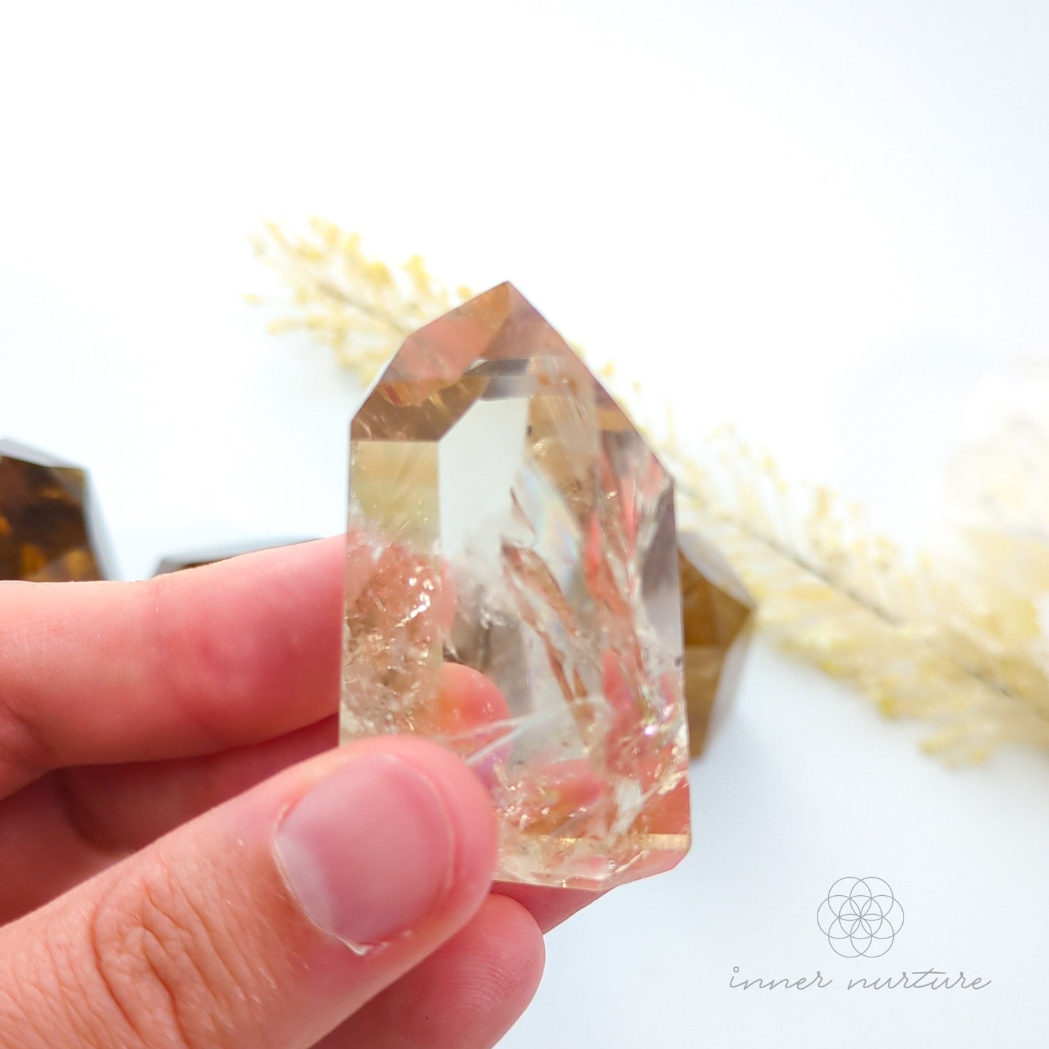 Hand holding a brown crystal with a blurred background. Set of crystal points on a white background with 'inner nurture' branding. Citrine (Natural) Tower for Abundance & Manifestation | Crystals Australia Inner Nurture