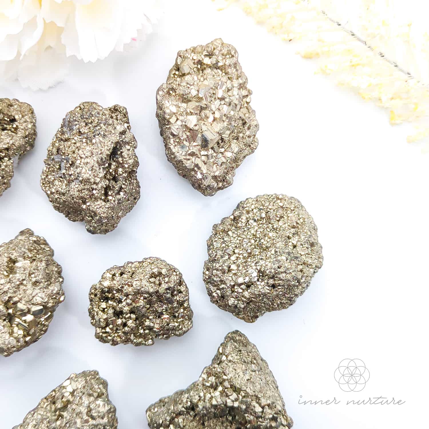 Pyrite crystals on a white background with 'inner nurture' branding. Pyrite crystal cluster available online at Inner Nurture Crystals Australia