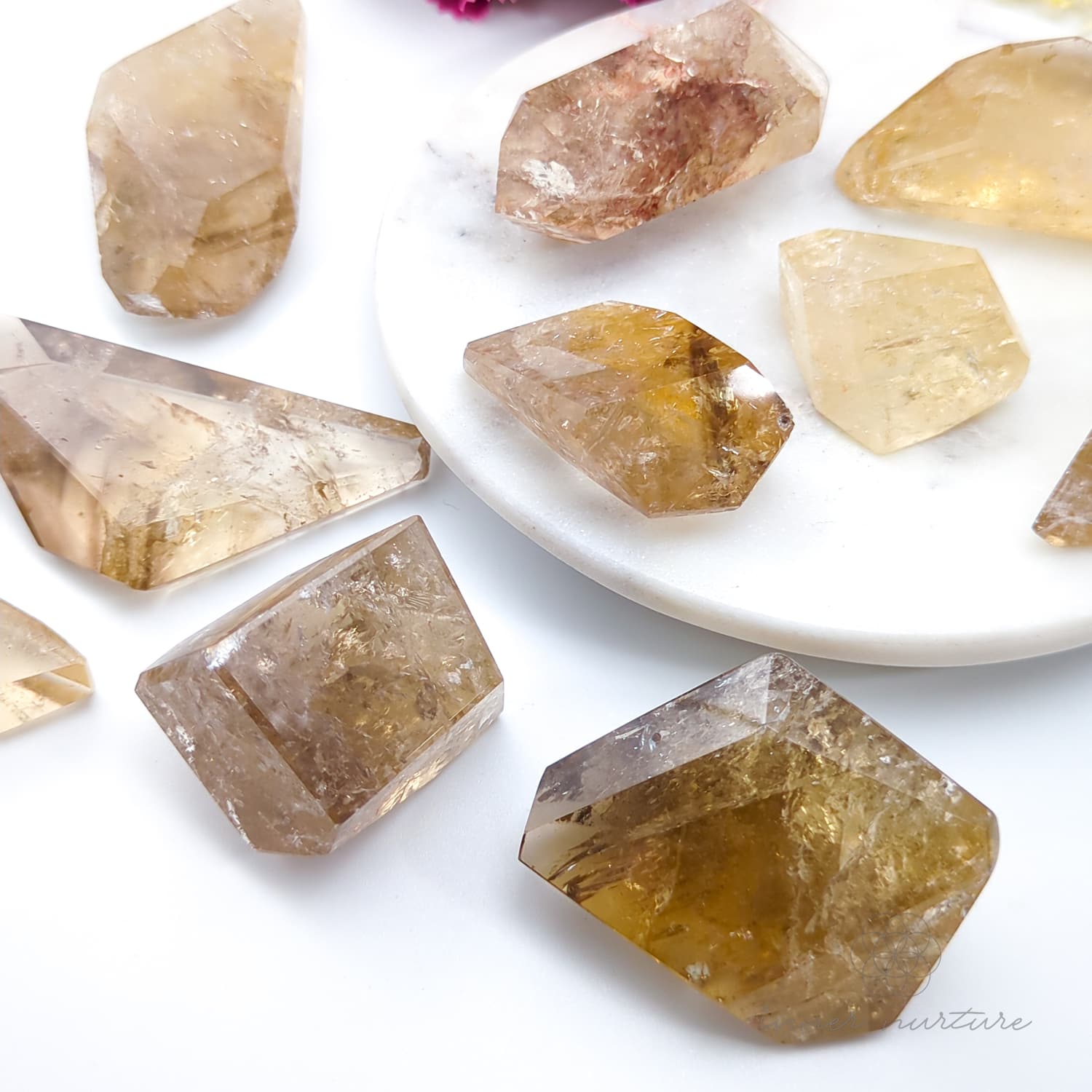 Hand holding four crystal rocks with a blurred background of flowers. Citrine (Natural) Free Form for Abundance & Manifestation | Crystals Australia Inner Nurture