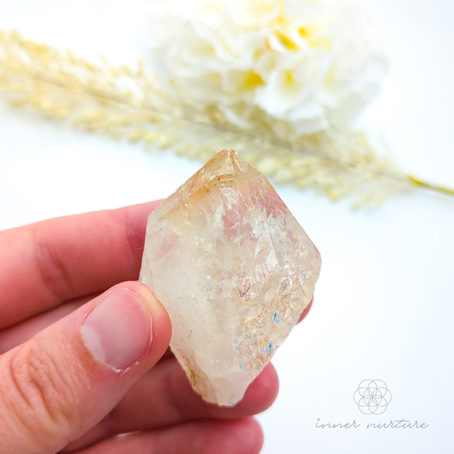 Hand holding a crystal with a blurred natural background. Citrine crystal available online at Inner Nurture Crystals Australia