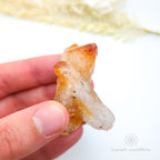 Hand holding a crystal with a blurred natural background. Citrine crystal available online at Inner Nurture Crystals Australia