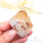 Hand holding a crystal with a blurred natural background. Citrine crystal available online at Inner Nurture Crystals Australia