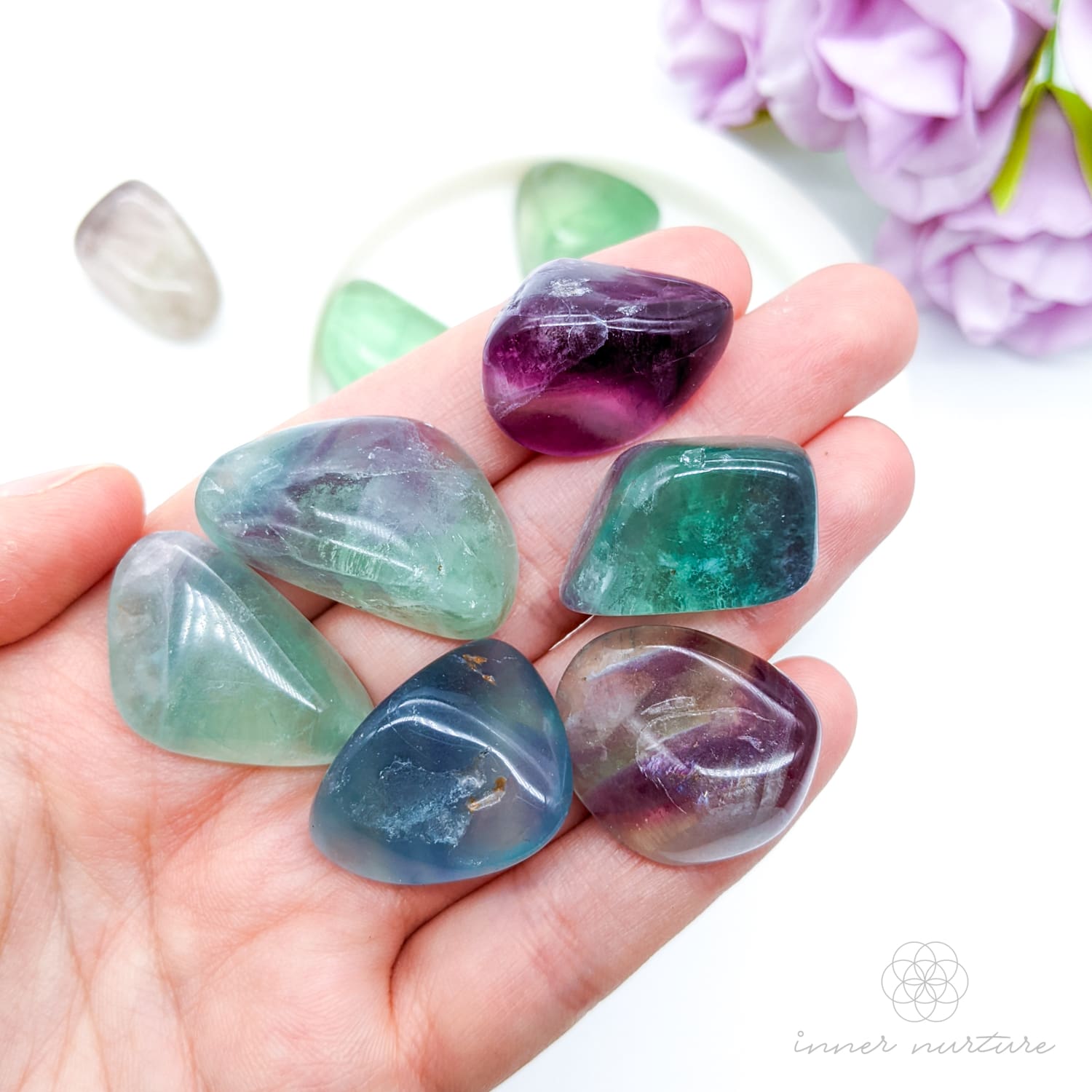 hand holding rainbow fluorite tumbles. available online at inner nurture, an online crystal shop in australia